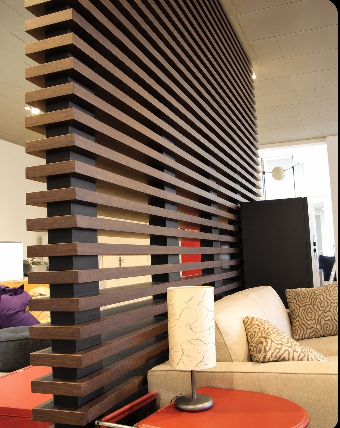 Celosía de madera oscura en diseño horizontal como divisor de sala con sofá beige y lámpara