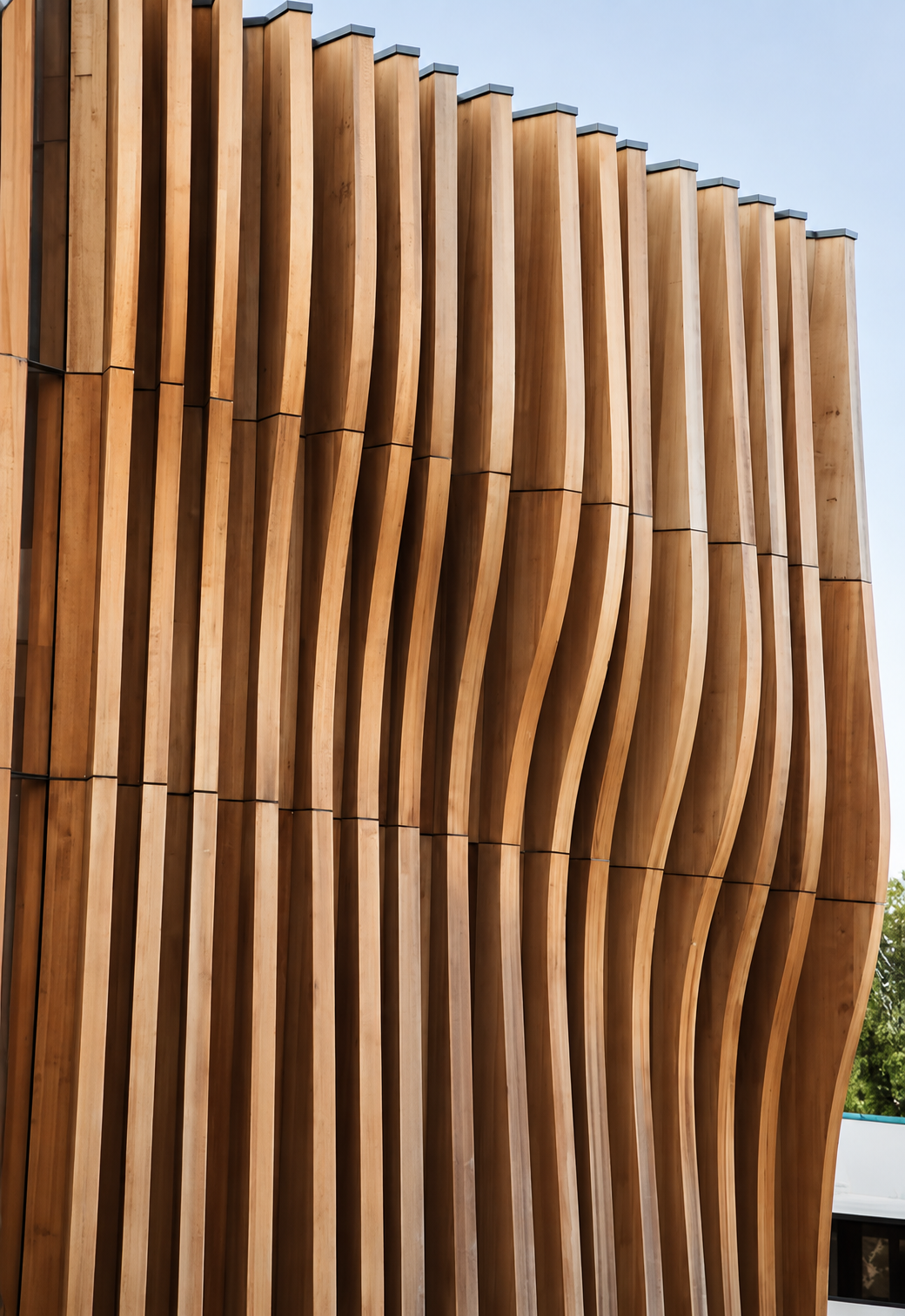 Fachada de carpintería exterior con listones verticales de madera ondulados y remates metálicos