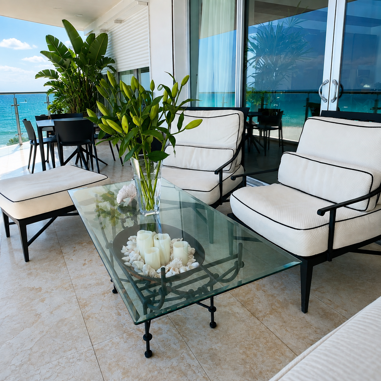 Terraza frente al mar con sillones blancos, mesa de cristal y vista al océano