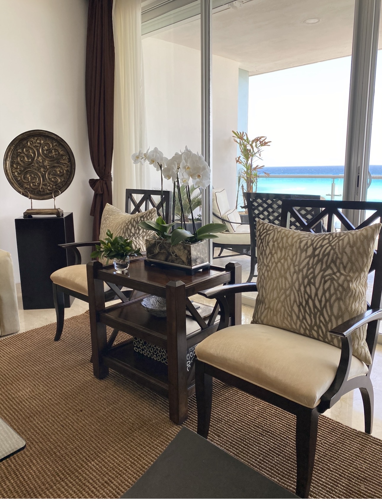 Comedor en terraza frente al mar con sillería oscura, orquídeas blancas y vista al océano