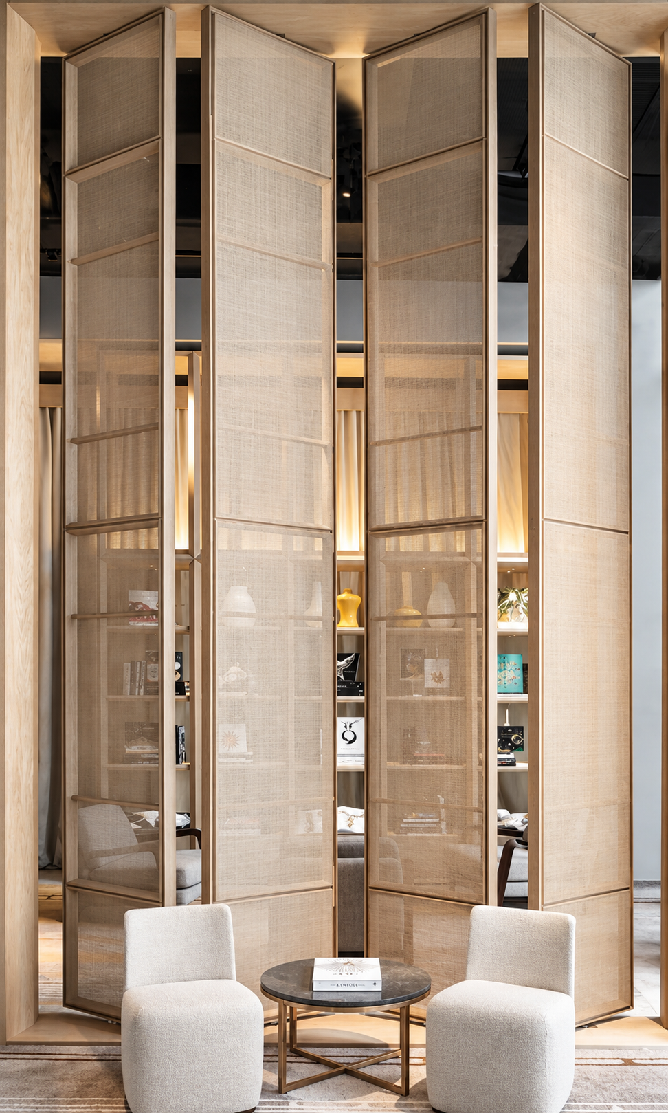 Biblioteca con puertas plegables de madera y malla, sillas tapizadas y mesa de centro
